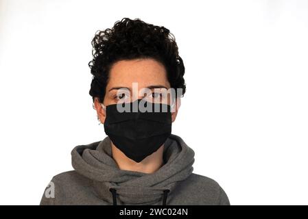 Donna che indossa una maschera nera su sfondo bianco Foto Stock