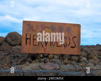 Cartello metallico per Los Hervideros. Sito culturale e attrazione turistica. Rocce laviche vicino al parco nazionale di Timanfaya. Isole Canarie, Lanzarote, Spagna Foto Stock