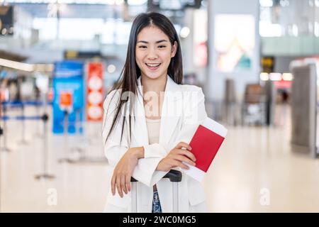 Una giovane donna asiatica con passaporto e bagagli al terminal dell'aeroporto Foto Stock