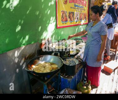 Una donna venditrice di cibo di strada che vende vari tipi di gorengan indonesiano o spuntini fritti di cibo di strada nella parte vecchia della città di Bandung, Giava Occidentale, Indonesia. Foto Stock