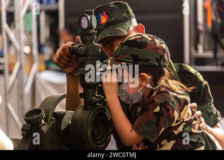 Bangkok, Thailandia. 13 gennaio 2024. Un soldato aiuta un bambino a guardare attraverso uno scopo di un lanciamissili durante la giornata dei bambini in Thailandia in una base dell'esercito reale thailandese a Bangkok. Credito: SOPA Images Limited/Alamy Live News Foto Stock