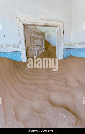 La sabbia del deserto copre completamente l'interno di una delle molte proprietà abbandonate dell'antica città fantasma di Kolmanskop nel sud della Namibia Foto Stock
