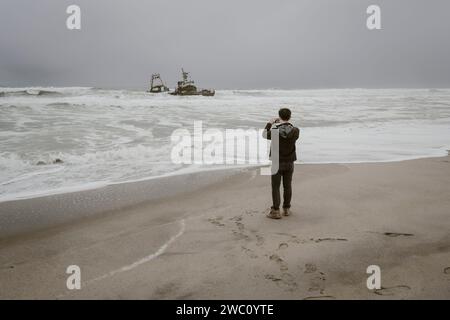 Un turista scatta una foto di uno dei relitti sulla Skeleton Coast in Namibia Foto Stock