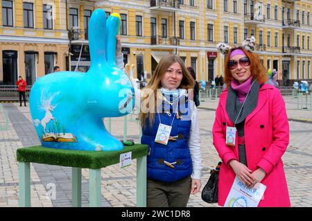 Ragazze sorridenti che guardano un'installazione di coniglio dipinta come un uovo di Pasqua ambientato su una strada. Festival dell'arte popolare. 18 aprile 2018. Kiev, Ucraina Foto Stock