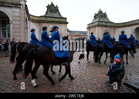 I soldati del reggimento ussari della guardia danese cavalcano fuori dalle scuderie reali del palazzo di Christiansborg mentre provano per domenica, quando la regina Margrethe II abdicò e suo figlio maggiore, il principe ereditario Frederik, salì al trono, a Copenaghen in Danimarca, sabato 13 gennaio 2024, Foto Stock