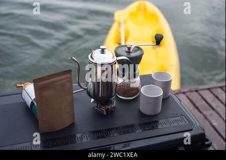 Set di macinacaffè manuale con tazza sul piano cottura a gas e tazza bianca Foto Stock