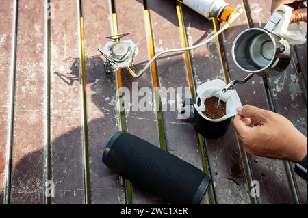 Versare acqua calda dal bollitore nel caffè macinato filtrato su una tazza. Preparare il caffè all'americana al mattino Foto Stock