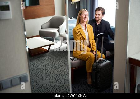 Una giovane coppia soddisfatta seduto sulla panchina nella camera d'albergo Foto Stock