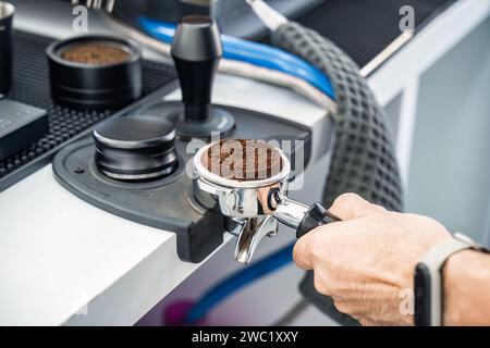 Barista che tiene portafiltro con caffè macinato in una caffetteria Foto Stock