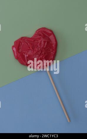 Caramelle regalo rosse a forma di cuore su uno sfondo di carta verde e blu. Foto Stock