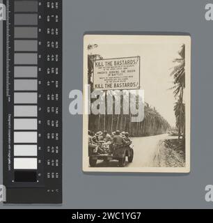 Jeep con soldati americani, con uno striscione con slogan anti-giapponesi, Anonymous, 1944 - 1945 sopra la strada Fotografia Boven de jeep hangt een spandoek met de tekst: "UCCIDETE I BASTARDI! / LUNGO QUESTA STRADA HA MARCIATO UNO DEI REGGIMENTI / DELL'ESERCITO DEGLI STATI UNITI / CAVALIERI AL SERVIZIO DELLA REGINA DELLE BATTAGLIE / VENTI DI LORO FERITI IN LETTIERE SONO STATI / BAYONETED, COLPITO E GRAFFIATO / DALLE PANCE GIALLE / UCCIDERE I BASTARDI! stampa di carta gelatina argento Foto Stock