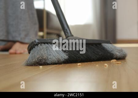 Pulizia della casa. Primo piano di una donna che fa i lavori domestici, tiene una scopa e spazza il pavimento Foto Stock