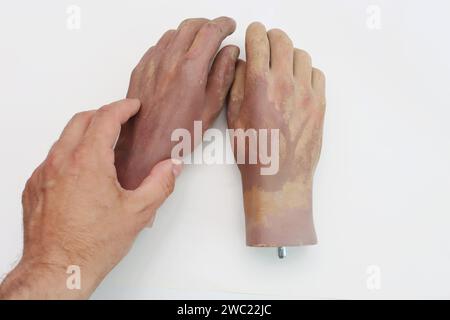 Mano che tiene la mano di plastica della bambola grande. Foto Stock