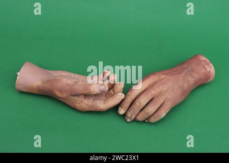 Due polsi dalla mano di un uomo da una bambola grande su sfondo verde. Foto Stock