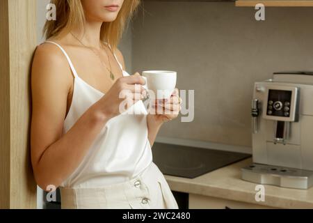 Bella donna che prende il suo primo caffè mattutino in cucina Foto Stock