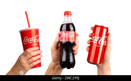 Lodz, Polonia maggio 26 2023 mani che tengono la bevanda Coca Cola in confezioni diverse, bottiglia di plastica, tazza di carta, può essere isolato su bianco Foto Stock