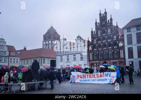 Greifswald, Germania. 13 gennaio 2024. Secondo la polizia, 1.200 persone hanno manifestato contro il razzismo nella piazza del mercato di Greifswald di fronte al municipio alla luce dei recenti attacchi nella città. Con il motto "Mostra la tua faccia - contro il razzismo”, i residenti di Greifswald hanno parlato in una manifestazione di sabato pomeriggio delle loro esperienze nella vita quotidiana, del loro lavoro, dei loro studi e del loro impegno sociale. Crediti: Stefan Sauer/dpa/Alamy Live News Foto Stock