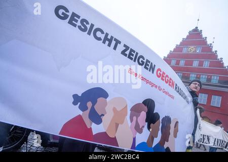 Greifswald, Germania. 13 gennaio 2024. Secondo la polizia, 1.200 persone hanno manifestato contro il razzismo nella piazza del mercato di Greifswald di fronte al municipio alla luce dei recenti attacchi nella città. Con il motto "Mostra la tua faccia - contro il razzismo”, i residenti di Greifswald hanno parlato in una manifestazione di sabato pomeriggio delle loro esperienze nella vita quotidiana, del loro lavoro, dei loro studi e del loro impegno sociale. Crediti: Stefan Sauer/dpa/Alamy Live News Foto Stock