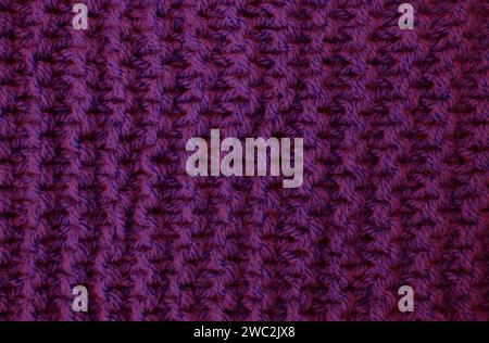 Primo piano sullo sfondo astratto di fili di lana in maglia viola. Foto Stock