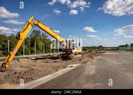 Costruzione di autostrade. Versamento di asfalto, installazione di barriere acustiche. Attrezzature per l'edilizia pesante in cantiere, rullo, escavatore, bulldozer Foto Stock