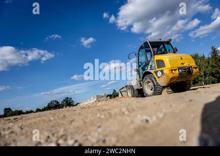 Costruzione di autostrade. Versamento di asfalto, installazione di barriere acustiche. Attrezzature per l'edilizia pesante in cantiere, rullo, escavatore, bulldozer Foto Stock