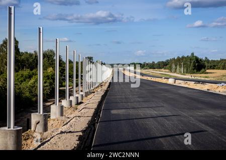 Costruzione di autostrade. Versamento di asfalto, installazione di barriere acustiche. Attrezzature per l'edilizia pesante in cantiere, rullo, escavatore, bulldozer Foto Stock