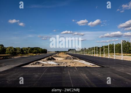 Costruzione di autostrade. Versamento di asfalto, installazione di barriere acustiche. Attrezzature per l'edilizia pesante in cantiere, rullo, escavatore, bulldozer Foto Stock