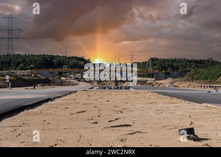 Costruzione di autostrade. Versamento di asfalto, installazione di barriere acustiche. Attrezzature per l'edilizia pesante in cantiere, rullo, escavatore, bulldozer Foto Stock