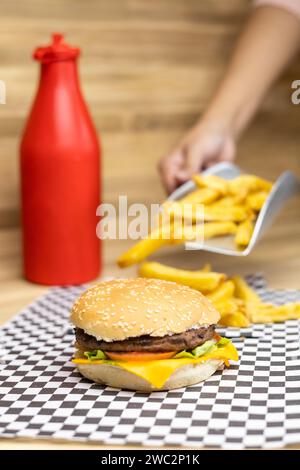 delizioso hamburger con formaggio, pane, carne, verdure e patatine fritte. fast food malsano, menu del ristorante in studio con salsa di pomodoro Foto Stock