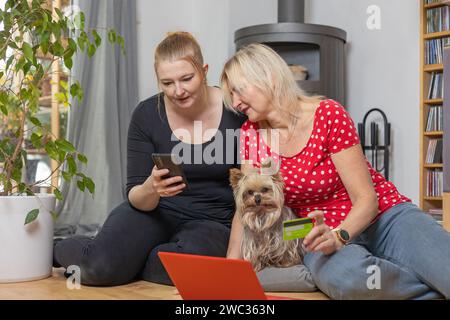 Madre e figlia controllano il pagamento online delle merci ordinate. Sicurezza per gli acquisti da casa. Foto Stock