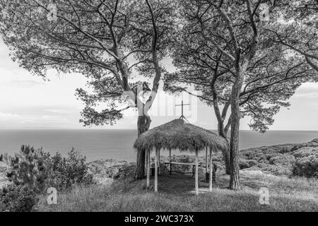 Piccola cappella improvvisata con tetto in paglia sotto i pini della tenuta delle Rippelte, fotografia in bianco e nero, Elba, Arcipelago Toscano Foto Stock