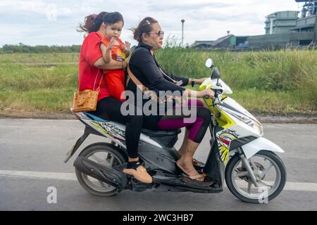 SAMUT SAKHON, THAILANDIA, DEC 03 2023, le donne guidano una moto con un bambino piccolo Foto Stock