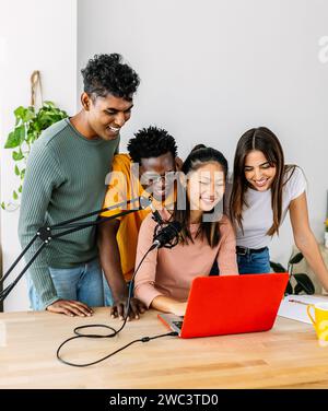 Un giovane gruppo di studenti che si diverte a fare podcast usando il laptop a casa Foto Stock