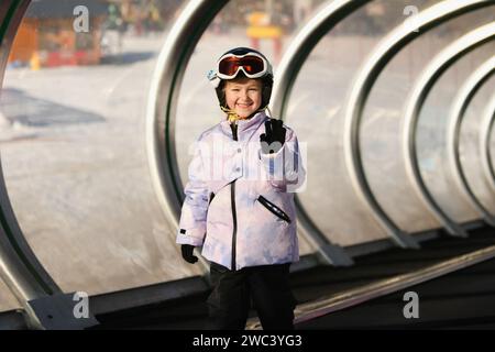 Una ragazza sugli sci è in piedi su uno skilift tappeto in una tunica Foto Stock