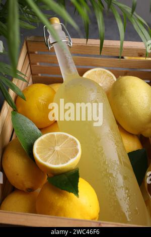 Gustoso liquore al limoncello, limoni e foglie verdi sul tavolo Foto Stock