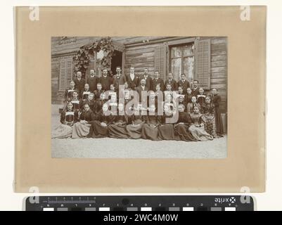 Ritratto di gruppo di una classe sconosciuta per un edificio in legno, Anonymous, 1890 - 1910 Fotografia scolastica con ragazze, ragazzi e insegnanti che si presentano come un gruppo per una carta baryta della casa. cartoncino anonimo persone storiche ritratte in un gruppo, in un ritratto di gruppo Foto Stock