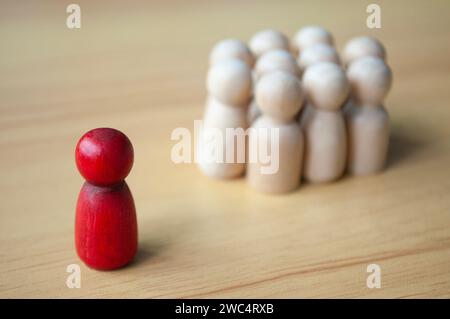 Una singola bambola di legno rossa separata da altre bambole. Rappresentare la leadership o l'isolamento. Foto Stock