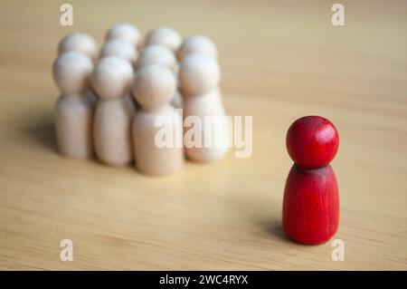 Una singola bambola di legno rossa separata da altre bambole. Rappresentare la leadership o l'isolamento Foto Stock