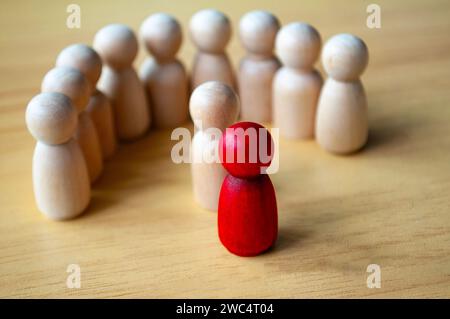 Bambola di legno rossa circondata da altre bambole. Rappresentare la leadership o le molestie Foto Stock