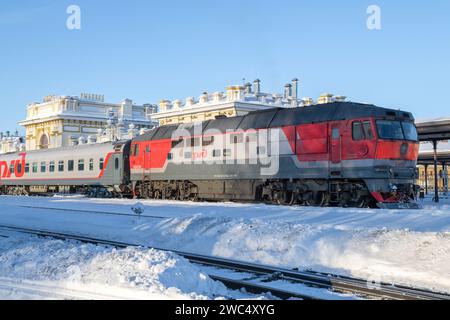 RYBINSK, RUSSIA - 3 GENNAIO 2024: Locomotiva diesel TEP70 con treno passeggeri alla stazione di Rybinsk in una soleggiata giornata di gennaio Foto Stock