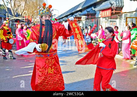 YANTAI, CINA - 14 GENNAIO 2024 - artisti popolari eseguono costumi popolari locali per celebrare il prossimo Festival di Primavera al mercato della Cultura Orientale di Foto Stock