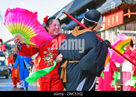 YANTAI, CINA - 14 GENNAIO 2024 - artisti popolari eseguono costumi popolari locali per celebrare il prossimo Festival di Primavera al mercato della Cultura Orientale di Foto Stock