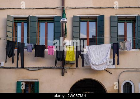 In una giornata di sole, una lavanderia colorata si appende al muro della casa per asciugarsi in tipico stile italiano. Foto Stock