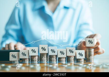 Concetto di tasso di interesse e dividendi, mettendo a mano il blocco di cubo di legno che aumenta sulla moneta di massa superiore con simbolo di percentuale icona, rendimento sulle scorte e. Foto Stock