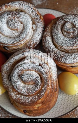 Dolci pasquali, kraffin con uva passa, frutta candita, cosparsa di zucchero in polvere. Primo piano della torta fatta in casa. Cruffin. Uova di Pasqua Foto Stock