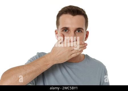 uomo che copre la bocca con le mani su sfondo bianco Foto Stock