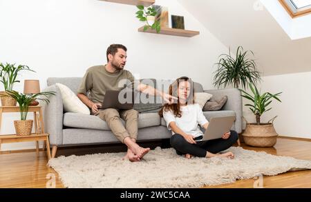 Coppia stile di vita domestico. Coppia seduto sul divano a casa e che usa un computer portatile. Foto Stock