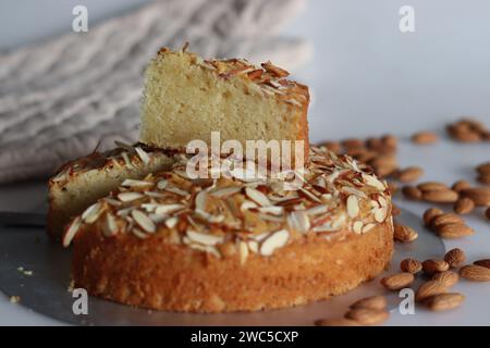 Torta al burro di mandorle a fette. Una deliziosa torta decorata con una spolverata generosa di mandorle tritate, perfetta per il tè. Facile da realizzare e visivamente Foto Stock