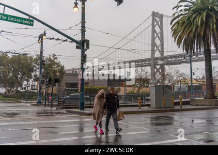 San Francisco, Stati Uniti. 13 gennaio 2024. La gente attraversa una strada sotto la pioggia a San Francisco, negli Stati Uniti, 13 gennaio 2024. Crediti: Li Jianguo/Xinhua/Alamy Live News Foto Stock