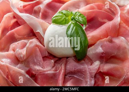 Prosciutto a fette con mozzarella e foglie di basilico, sfondo a cornice intera Foto Stock